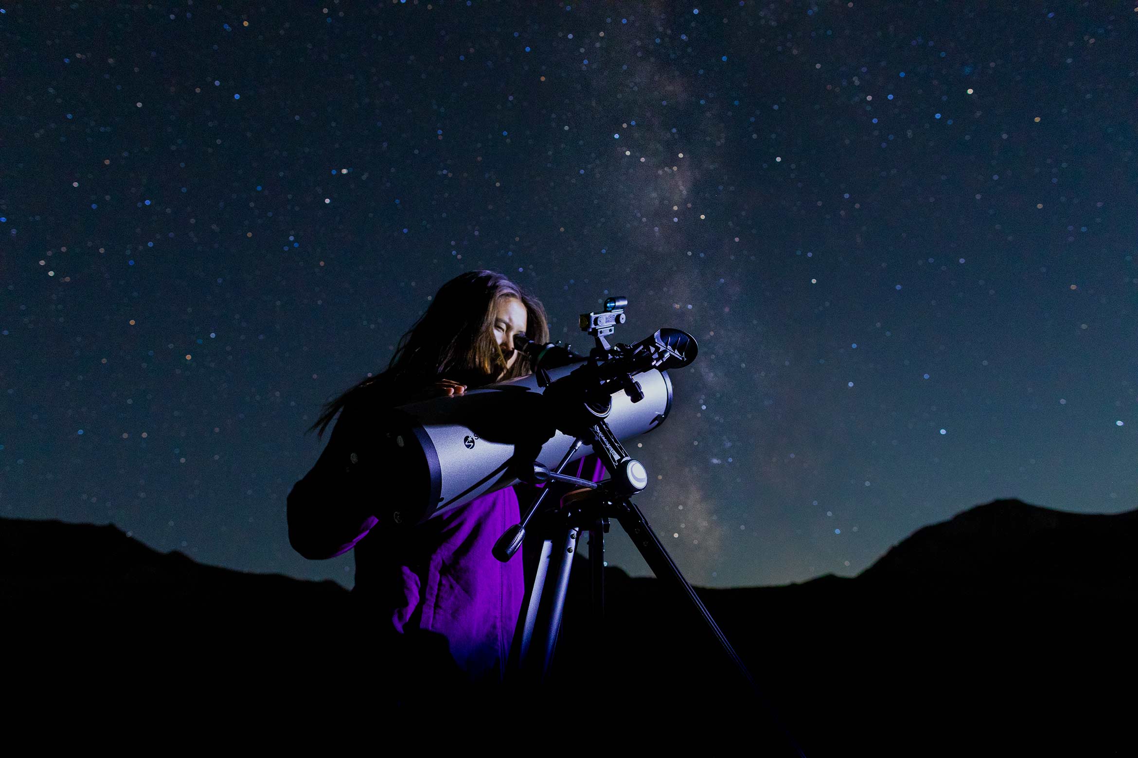 student using telescope with the Milky Way visible