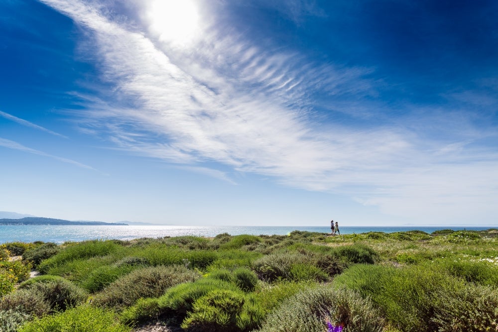 Two women walking on the cliffs above Campus Point at UCSB