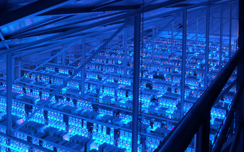 A data center glows blue with the light of thousands of servers