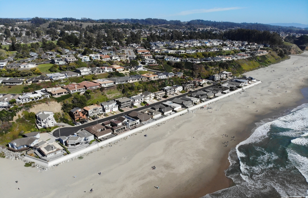Beachgoers enjoy the shoreline in front of coastal development at Rio Del Mar, Santa Cruz County. A seawall protects the first row of houses from the rising sea.