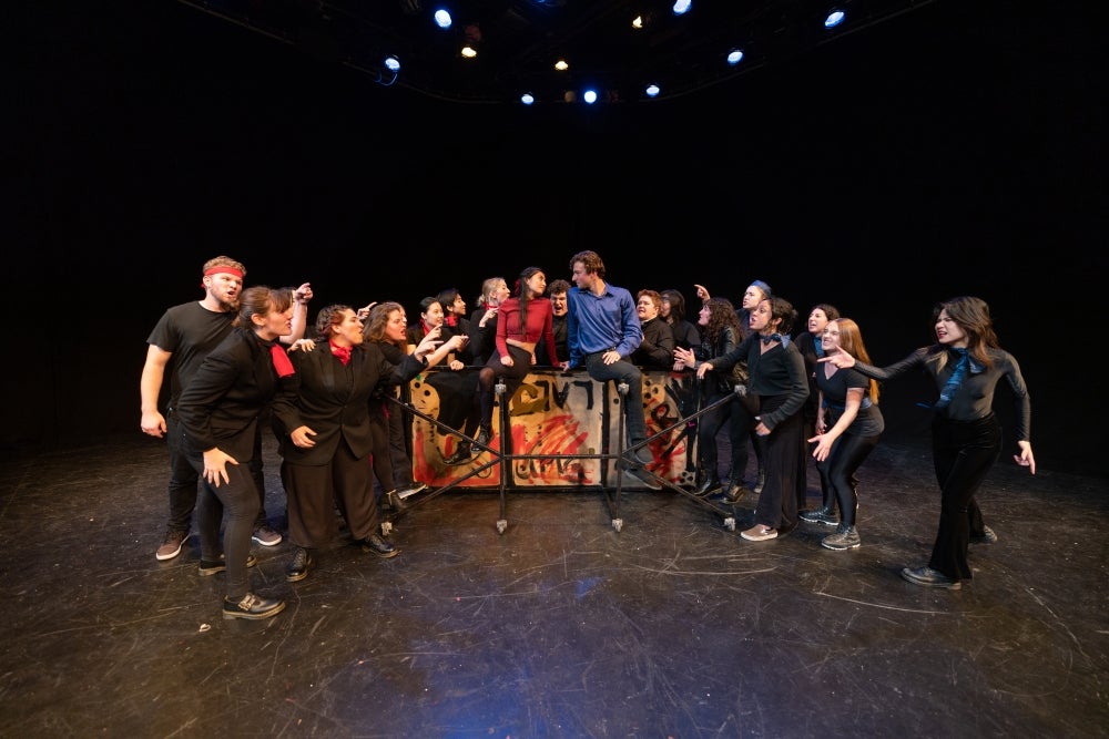 Actors dressed in black posed onstage