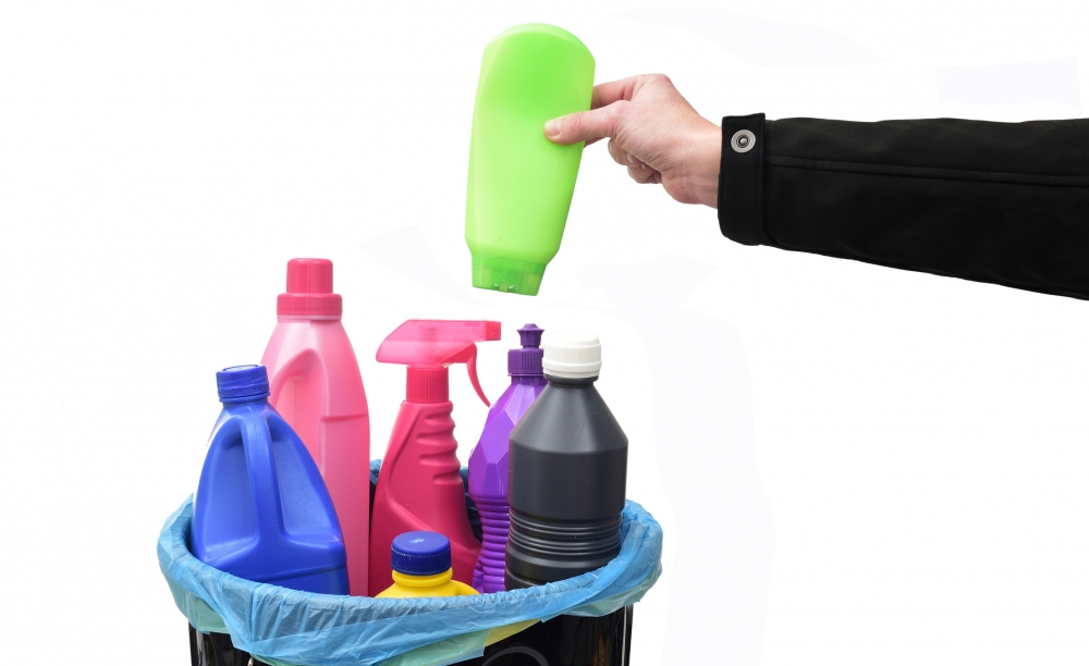 Hand grabbing bottle made of #2 and #4 plastic from trash bin with other plastic bottles