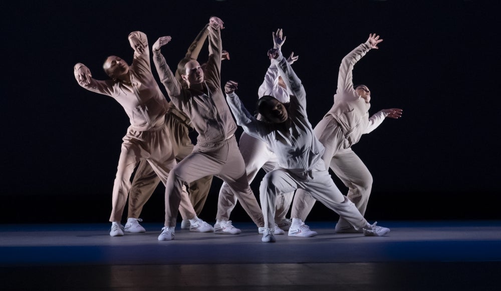 Dancers posing dramatically in a group on stage