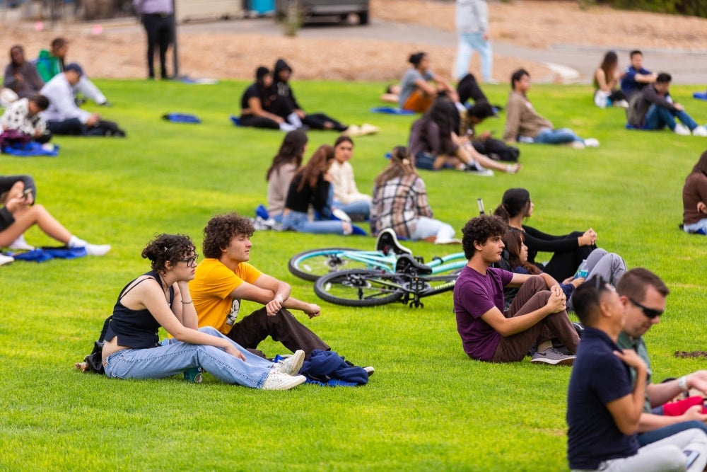 students sitting on green lawn at new student convocation