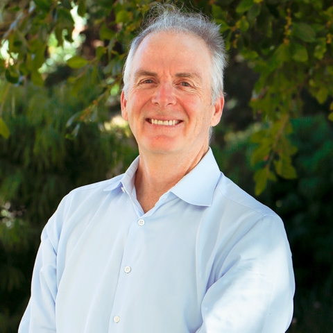 Craig Hawker stands outside in a light blue button-up shirt