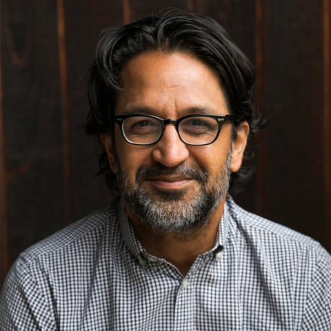 Sameer Pandya wears a checkered black & white shirt and glasses