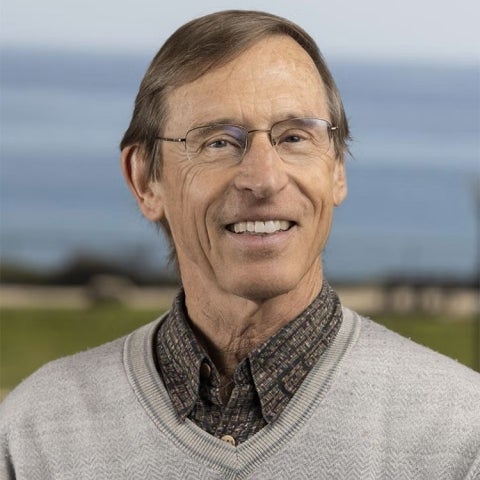 John Melack wears a sweater and a collared shirt