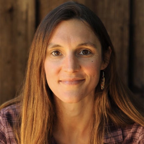 Liz Carlisle wears a flannel shirt outside a wooden structure