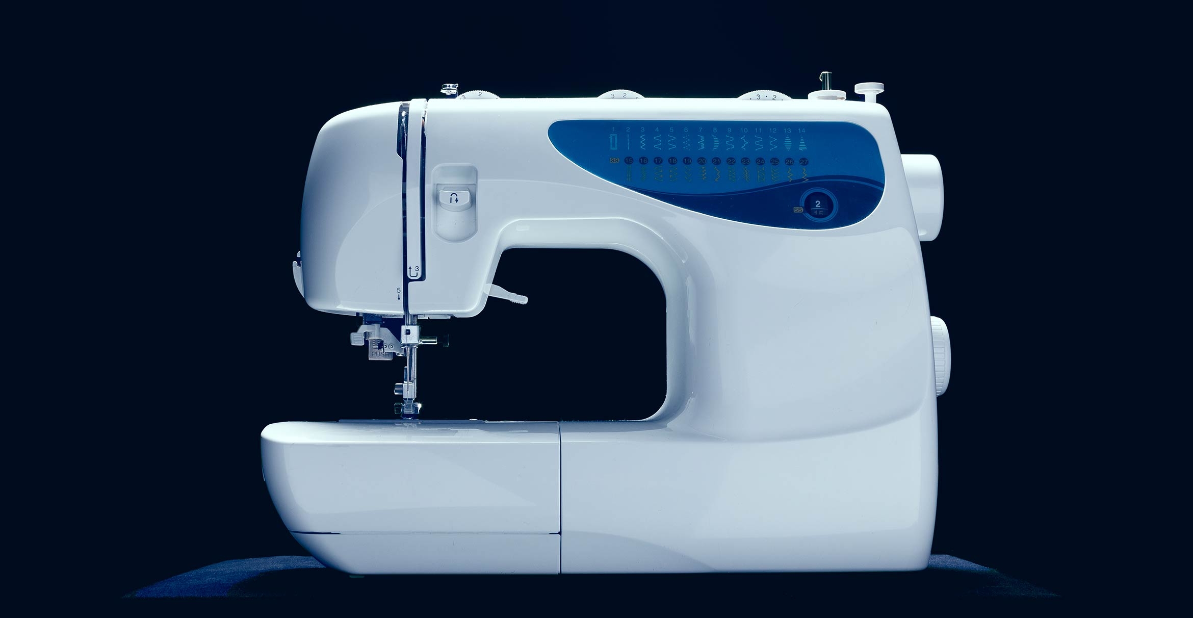 A sewing machine against a black background.