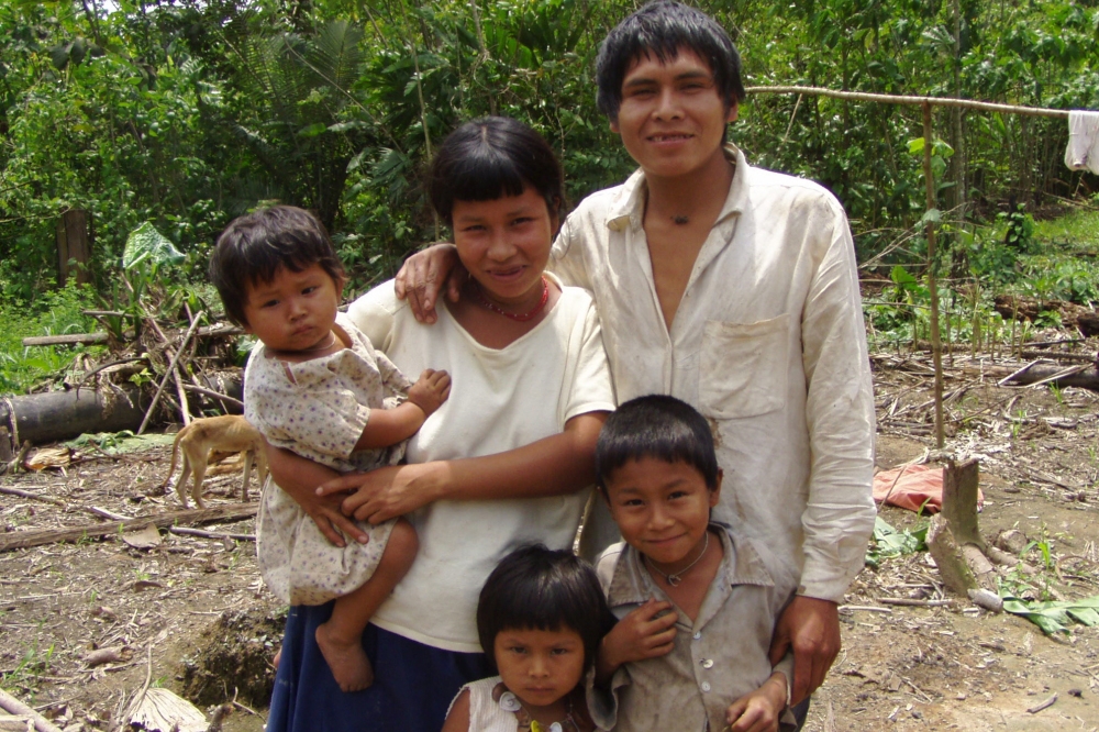 A family, made up of a couple and their three children, in the Amazon stands together smiling.