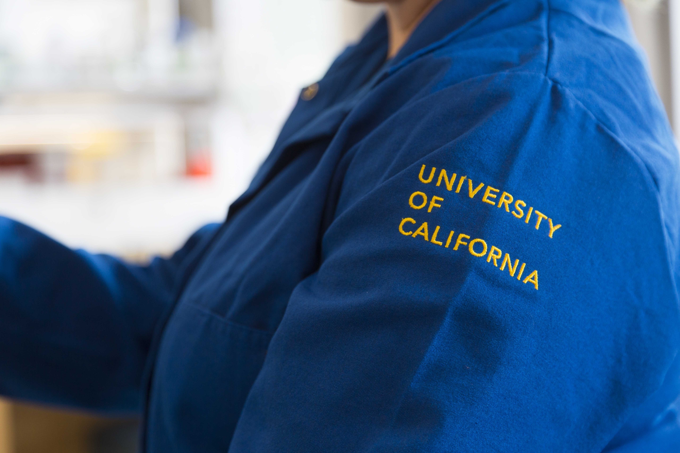 blue lab coat with UNIVERSITY OF CALIFORNIA in yellow stitching