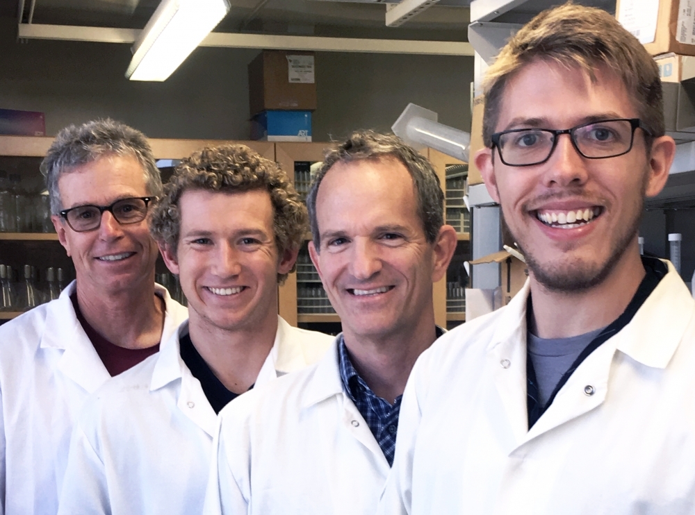 Four men in white labcoats standing in a line