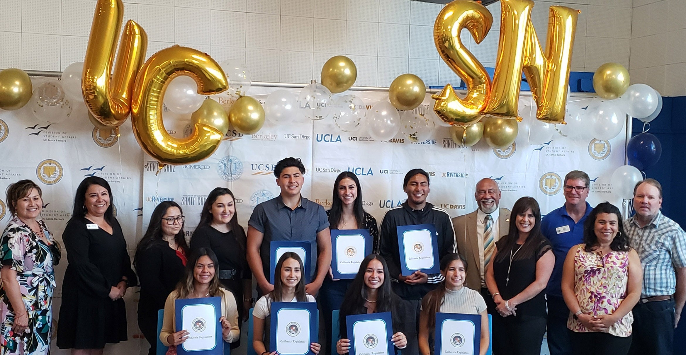 Two rows of college-age students holding certificates and smiling