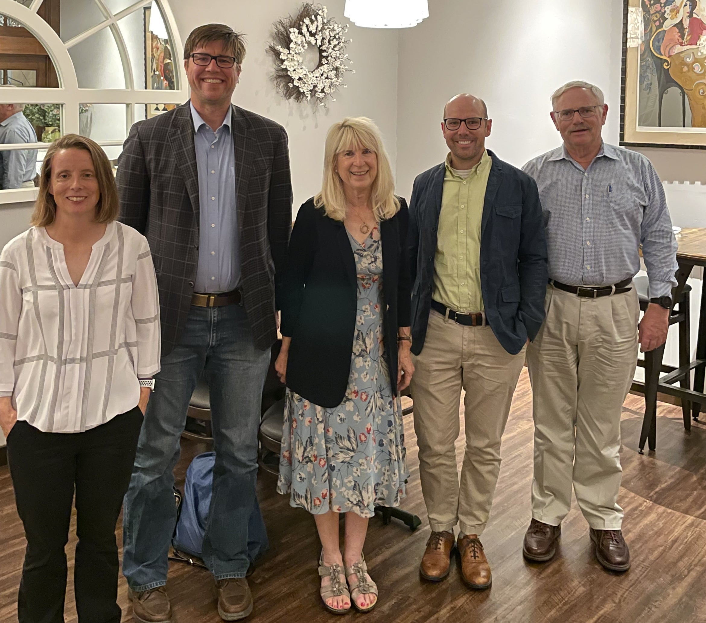 Five adults standing shoulder to shoulder in a restaurant