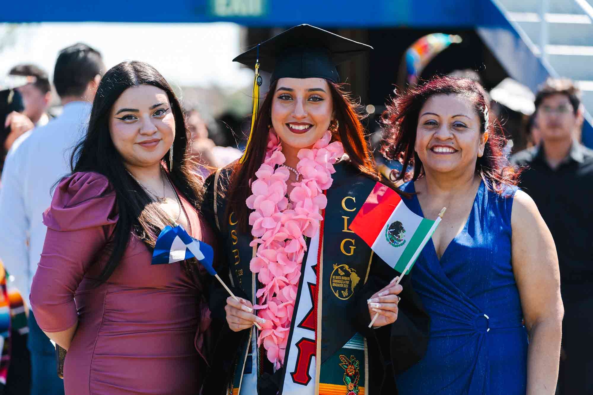 Graduate at center with family members holding Mexican flag