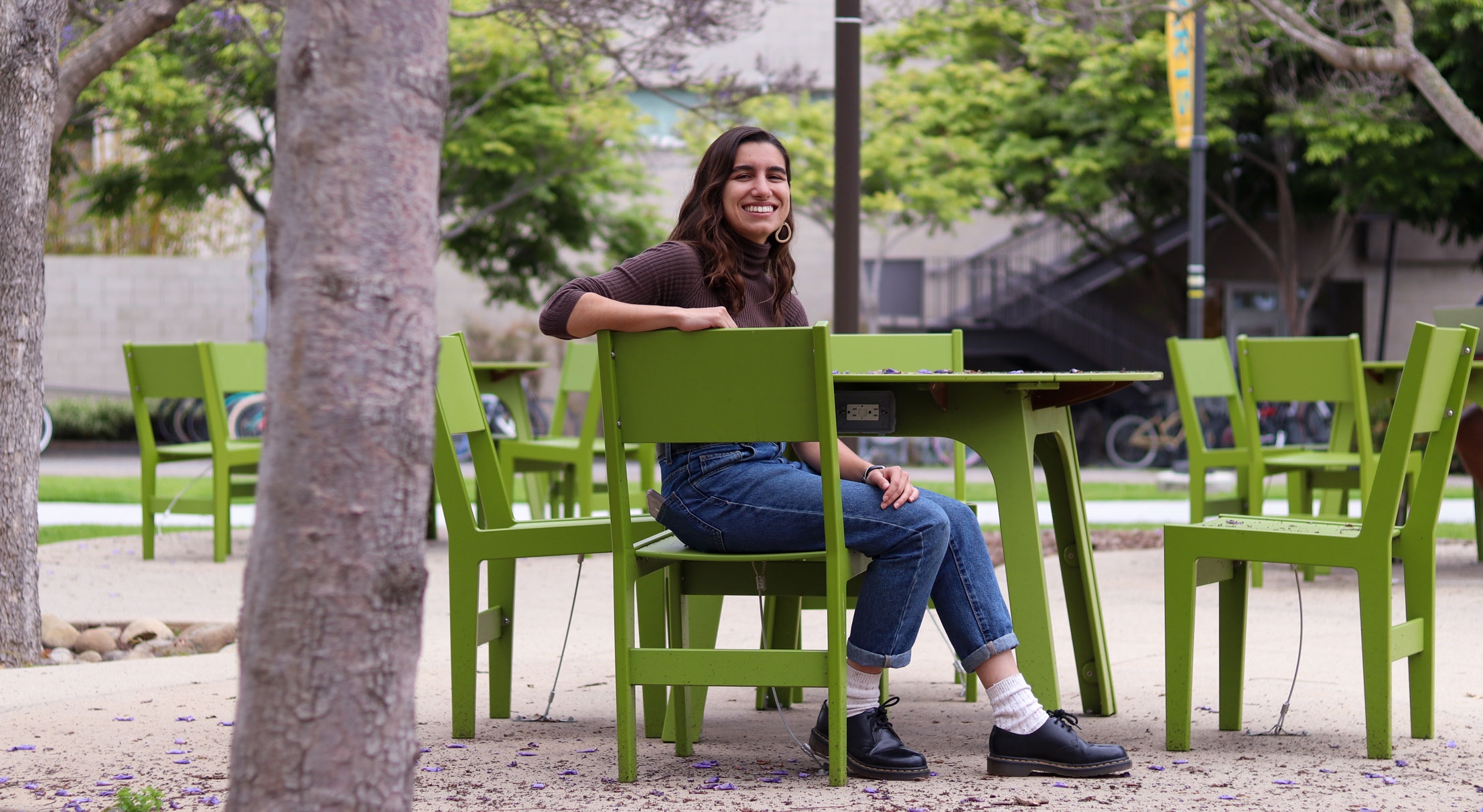 Student sits at lime green table under a tree