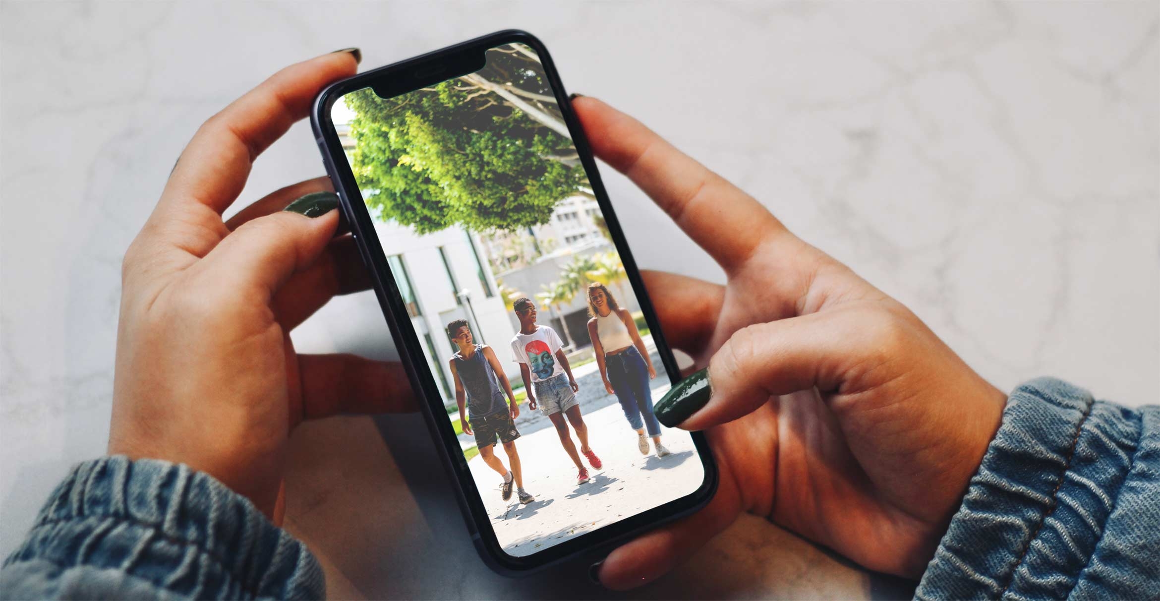 A person holds a phone displaying an image of a diverse group of people.