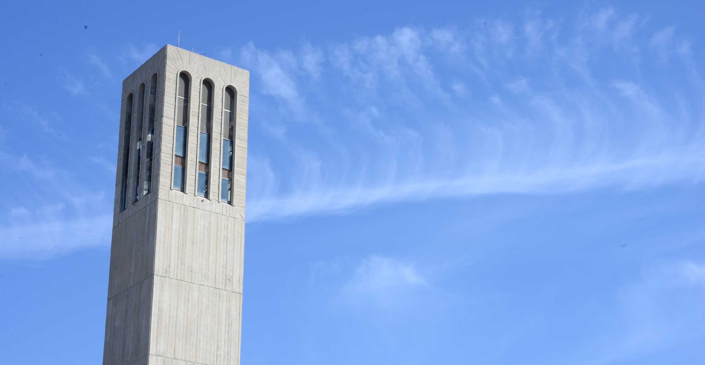 A tall grey tower against a bright blue sky