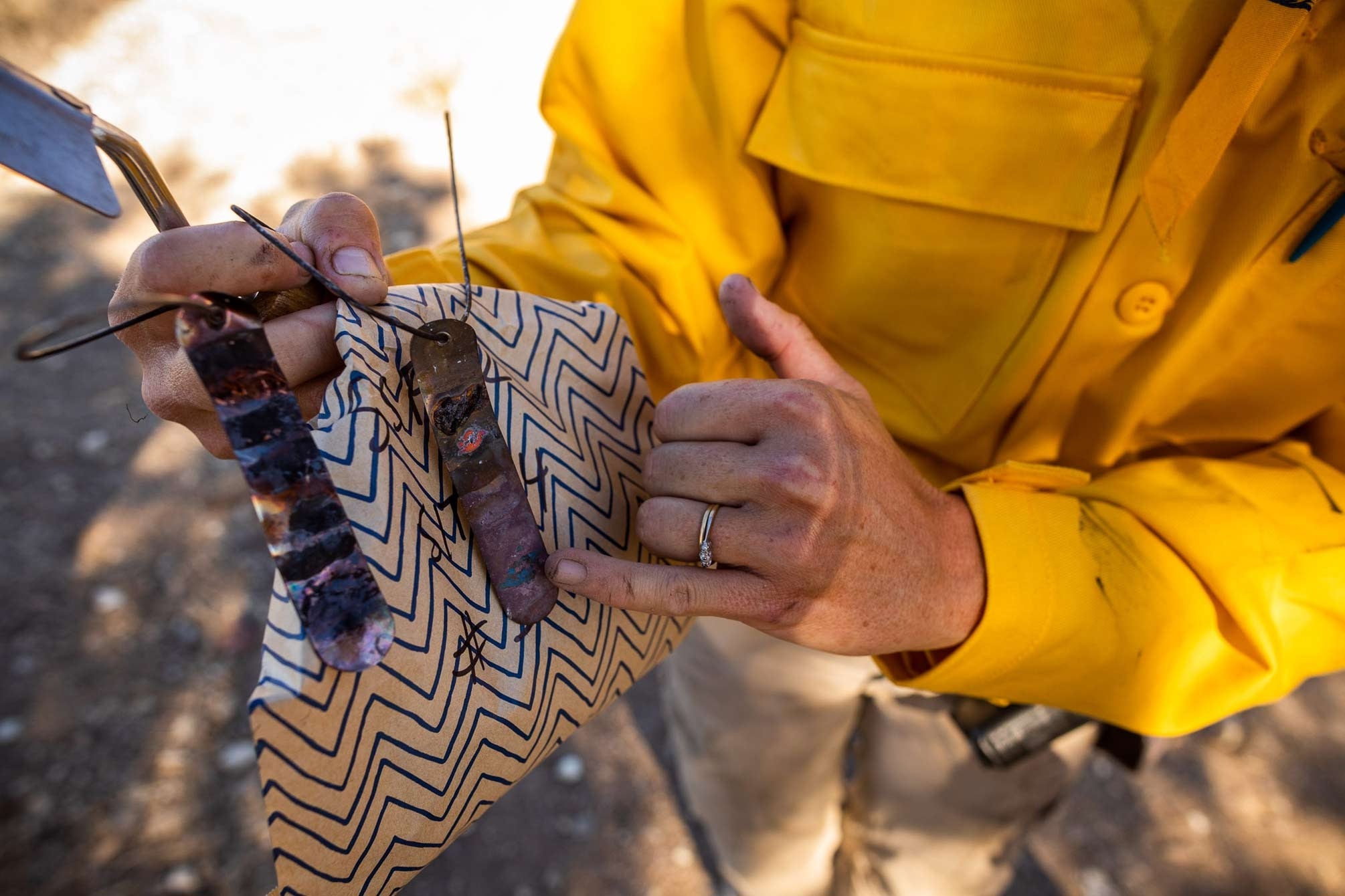  A researcher points to charred metal tags retrieved from a burn.The swatches of paint on these metal tags melt at different temperatures, indicating how hot the fire got at a particular location.