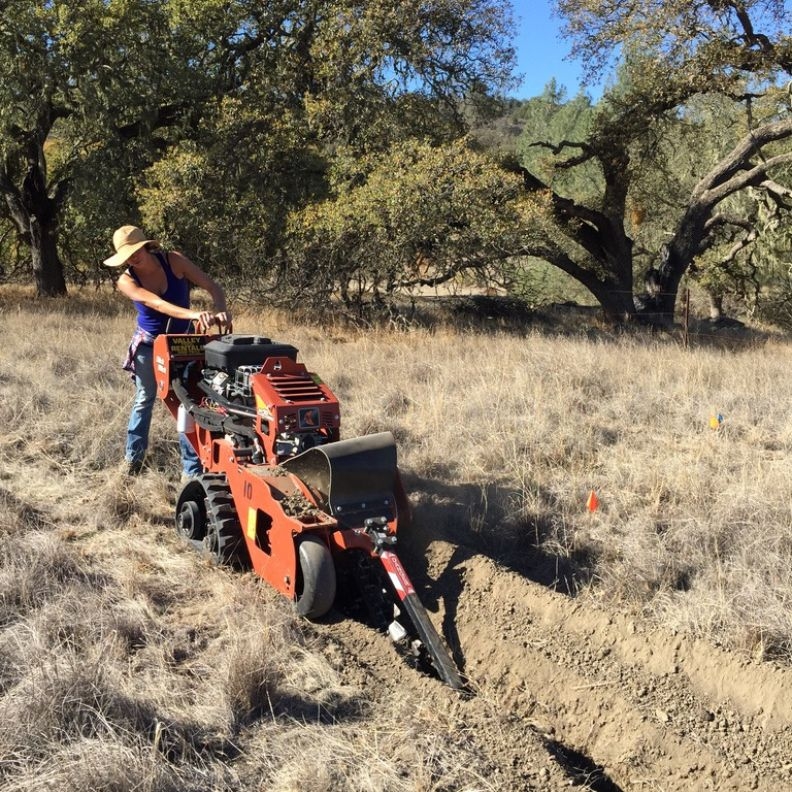 A researcher trenches around an experimental area at Sedgwick to stop from flowing into the test plot.