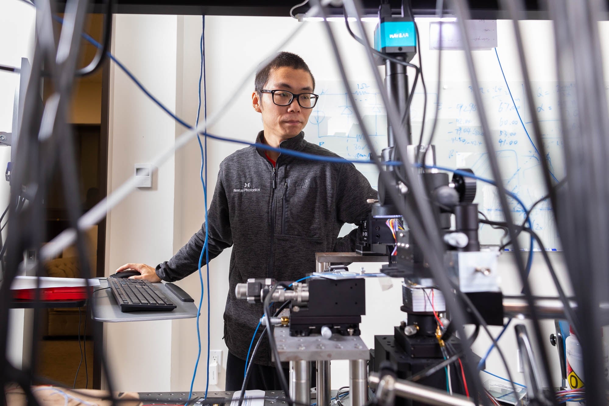 A researcher stands among cabling