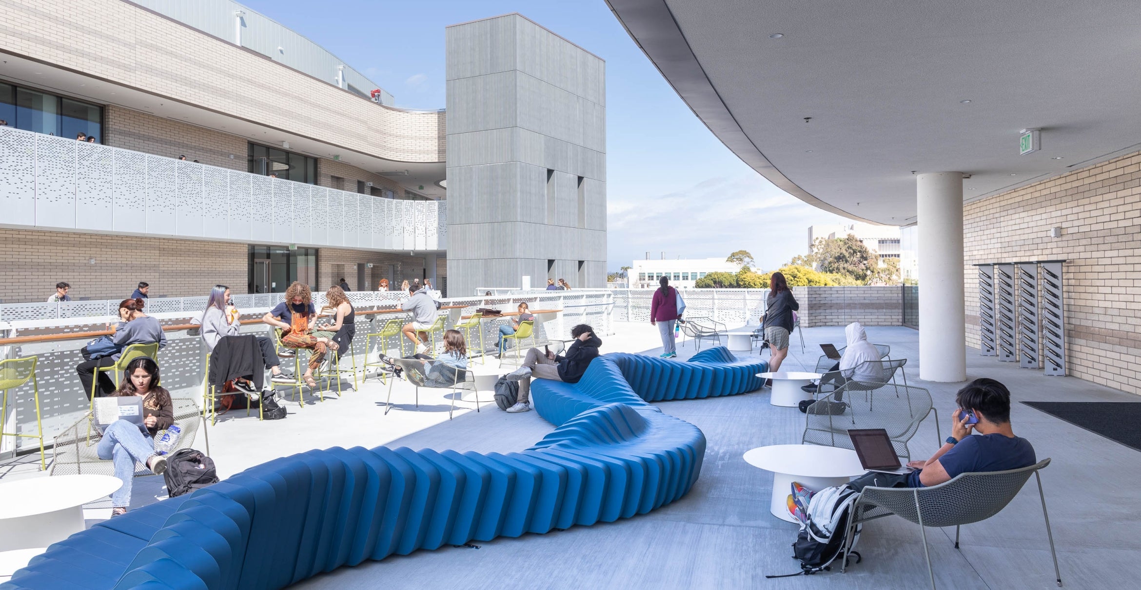 Students study and lounge on outdoor furniture.