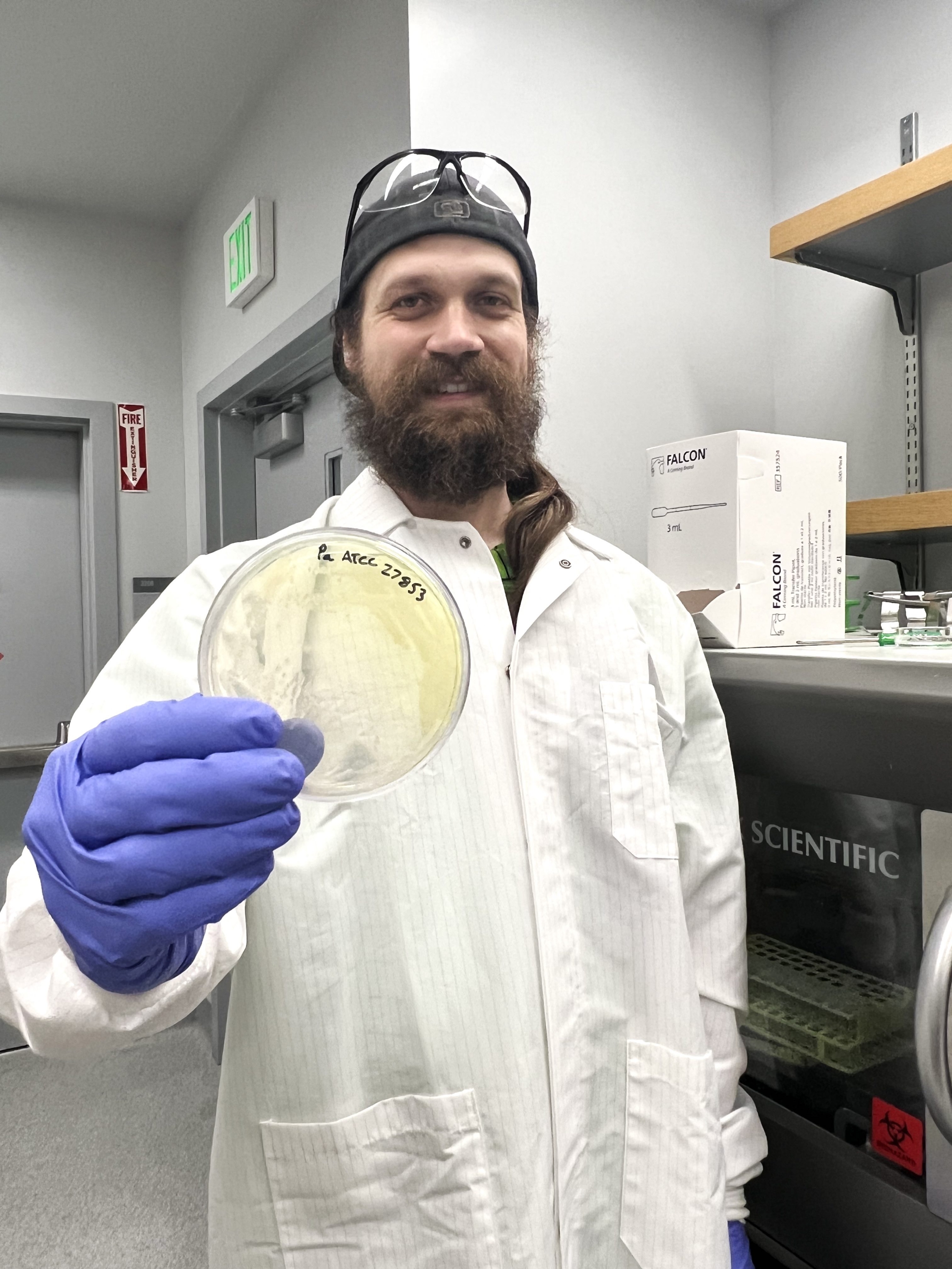 scientist in white lab coat with a petri dish
