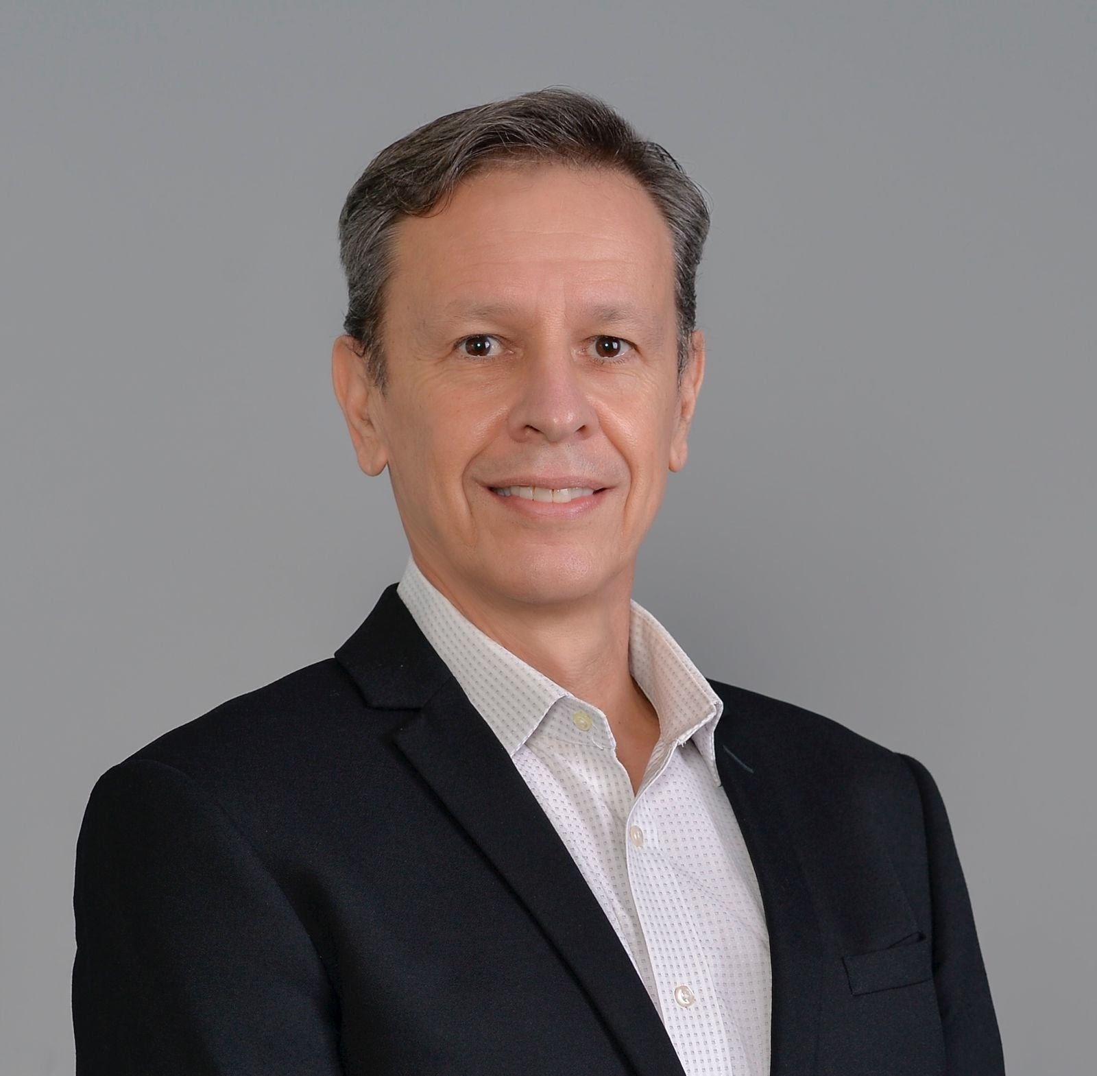 portrait of a man in a black suitjacket and white shirt against a gray background