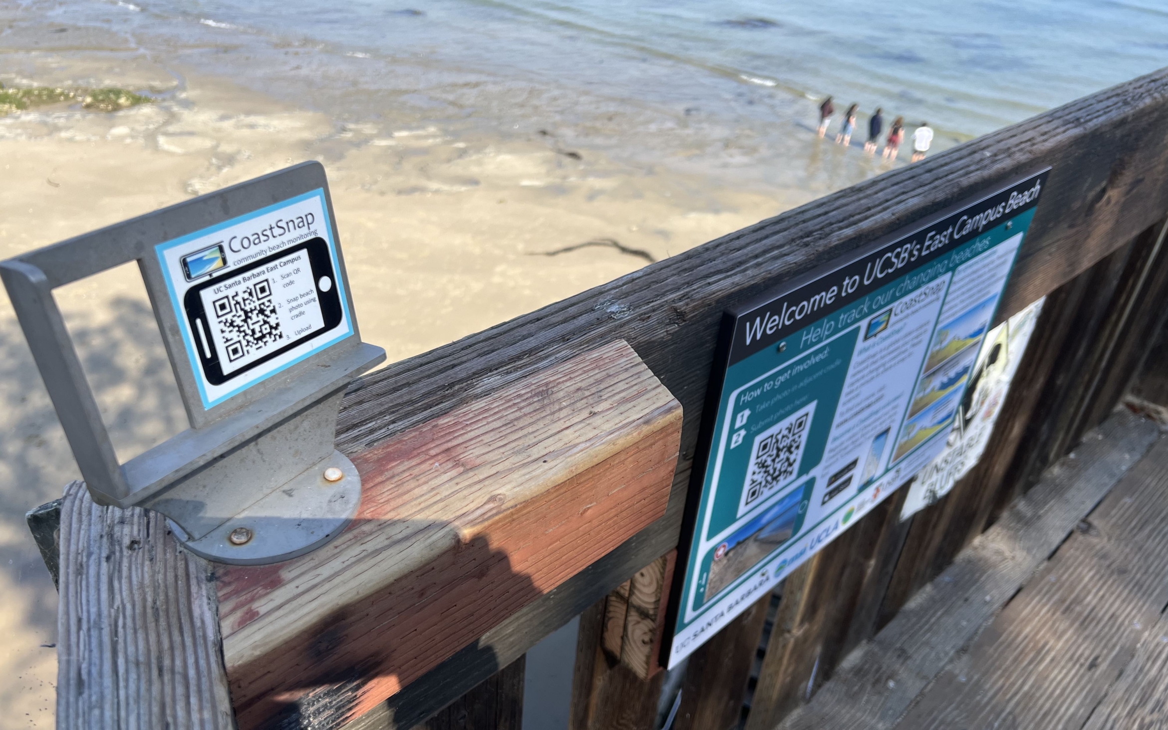 a photo cradle attached to the rail of steps leading to beach