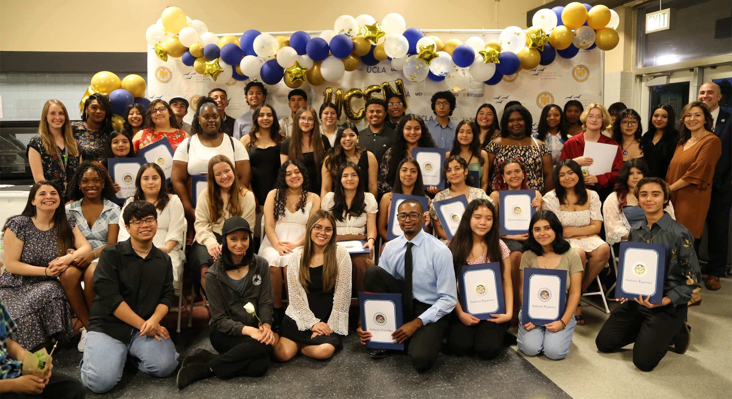 A large diverse group of students and adults surrounded by balloons