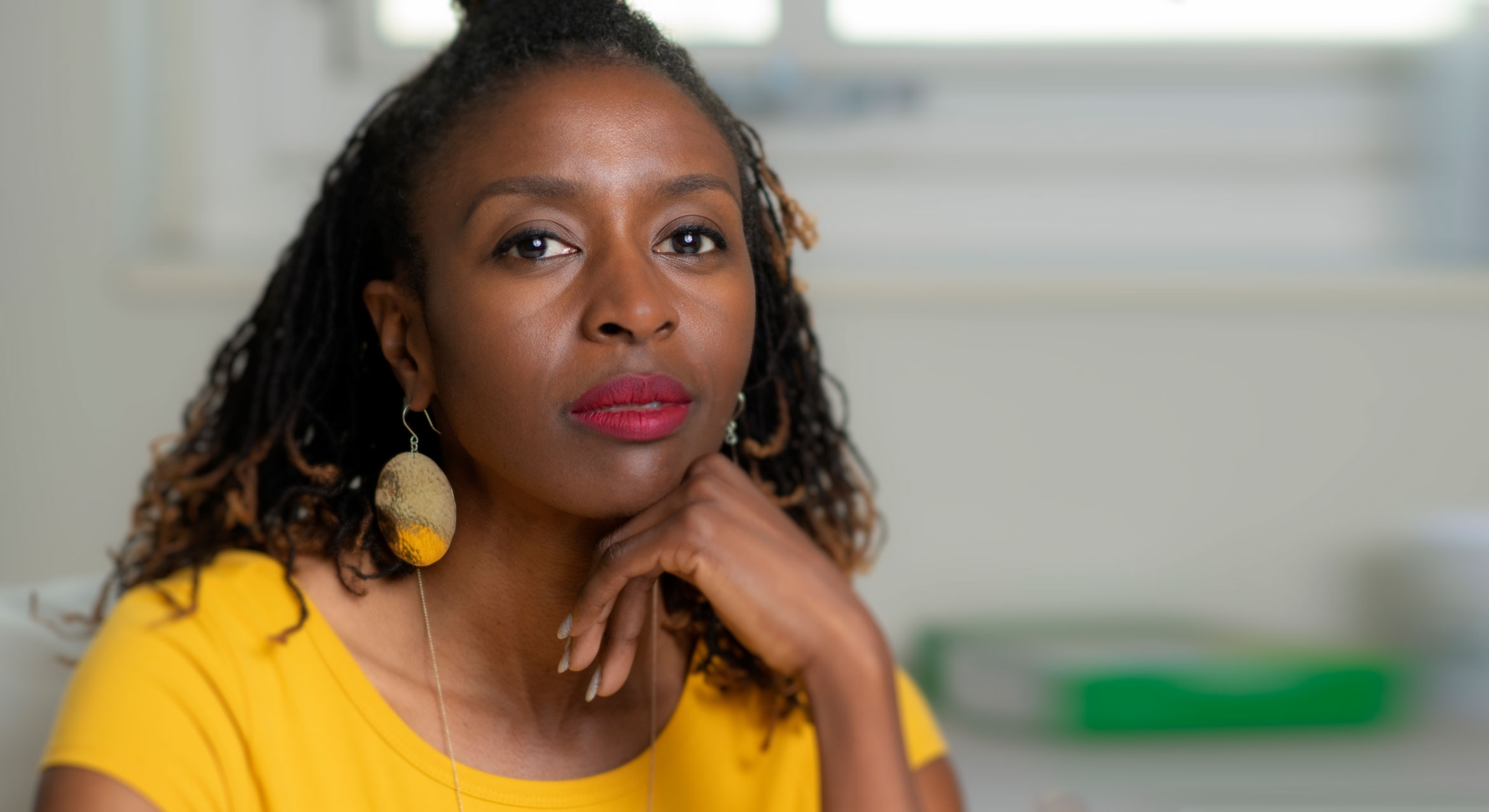 Headshot of Sabrina Strings a Black woman with yellow shirt and drop earings