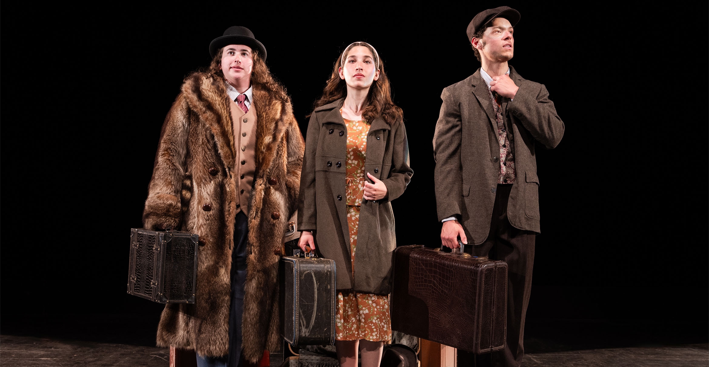 Three costumed actors - two men and one women - on a darkened stage