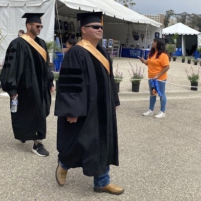 Kevin Schmidt walks in full commencement regalia