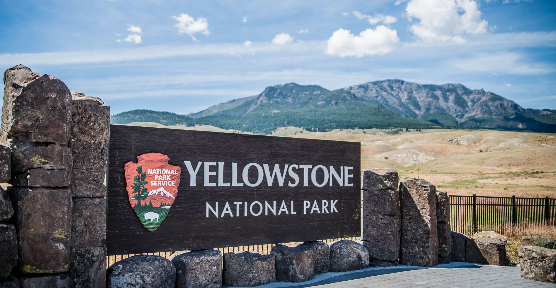 Yellowstone National Park sign with mountains in the background.