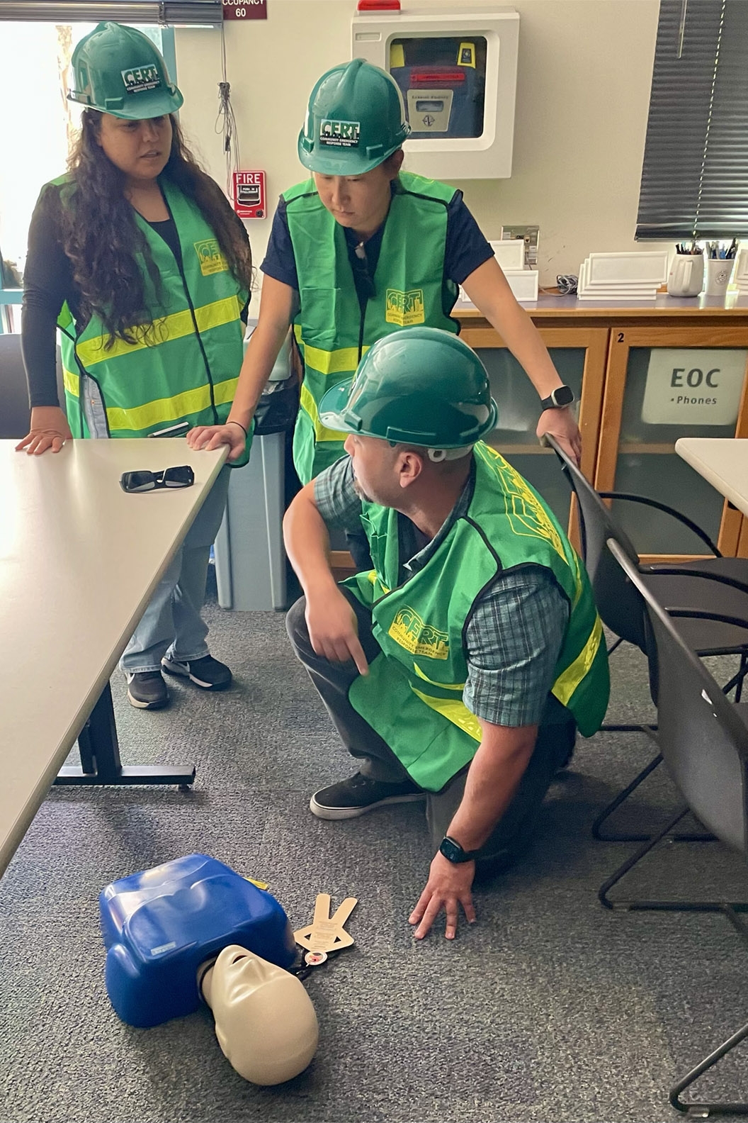 CERT trainees wear hard hats and high-vis vests as they attend to a CPR mannequin