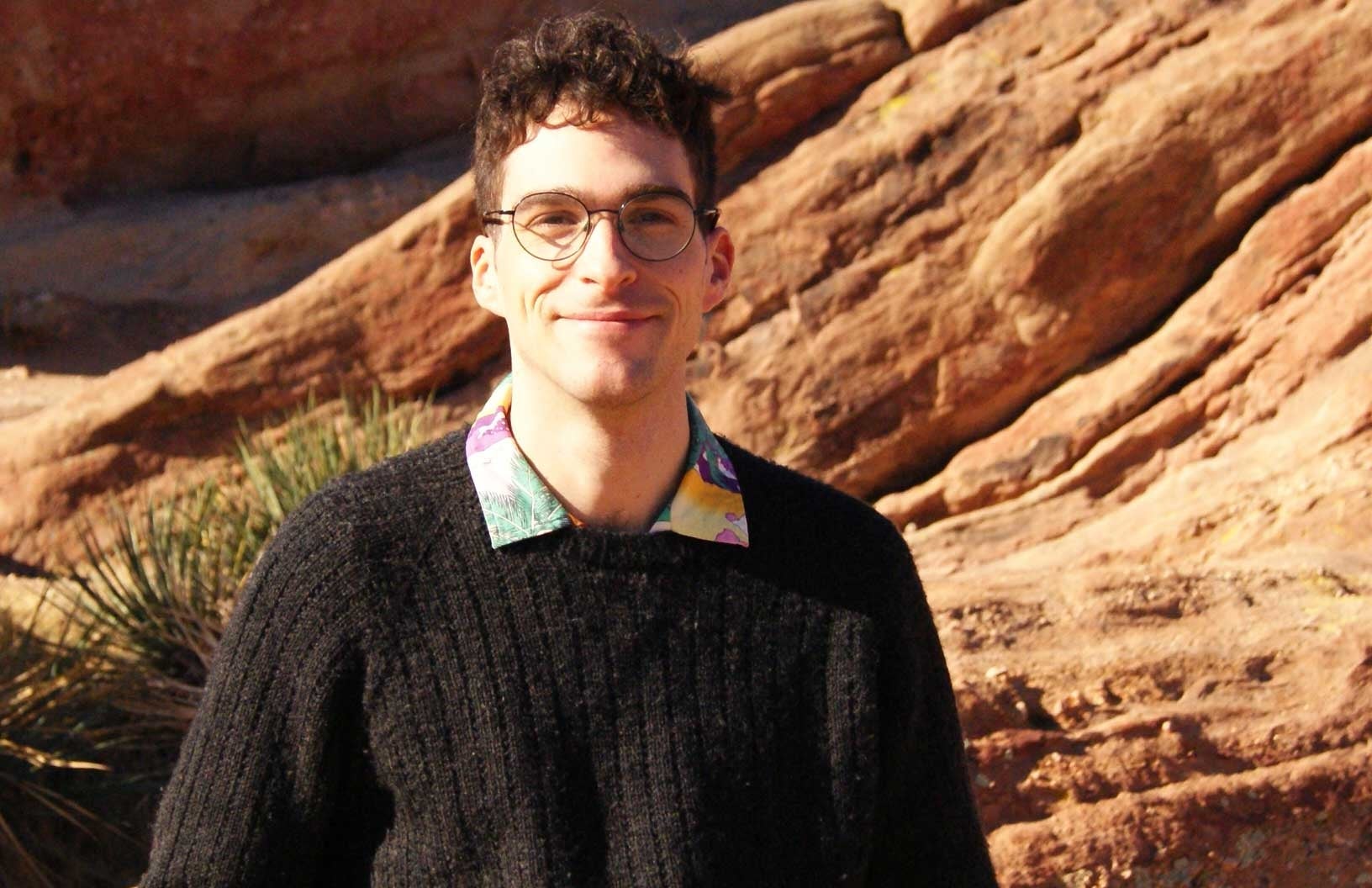 white man with glasses with rocky boulder 