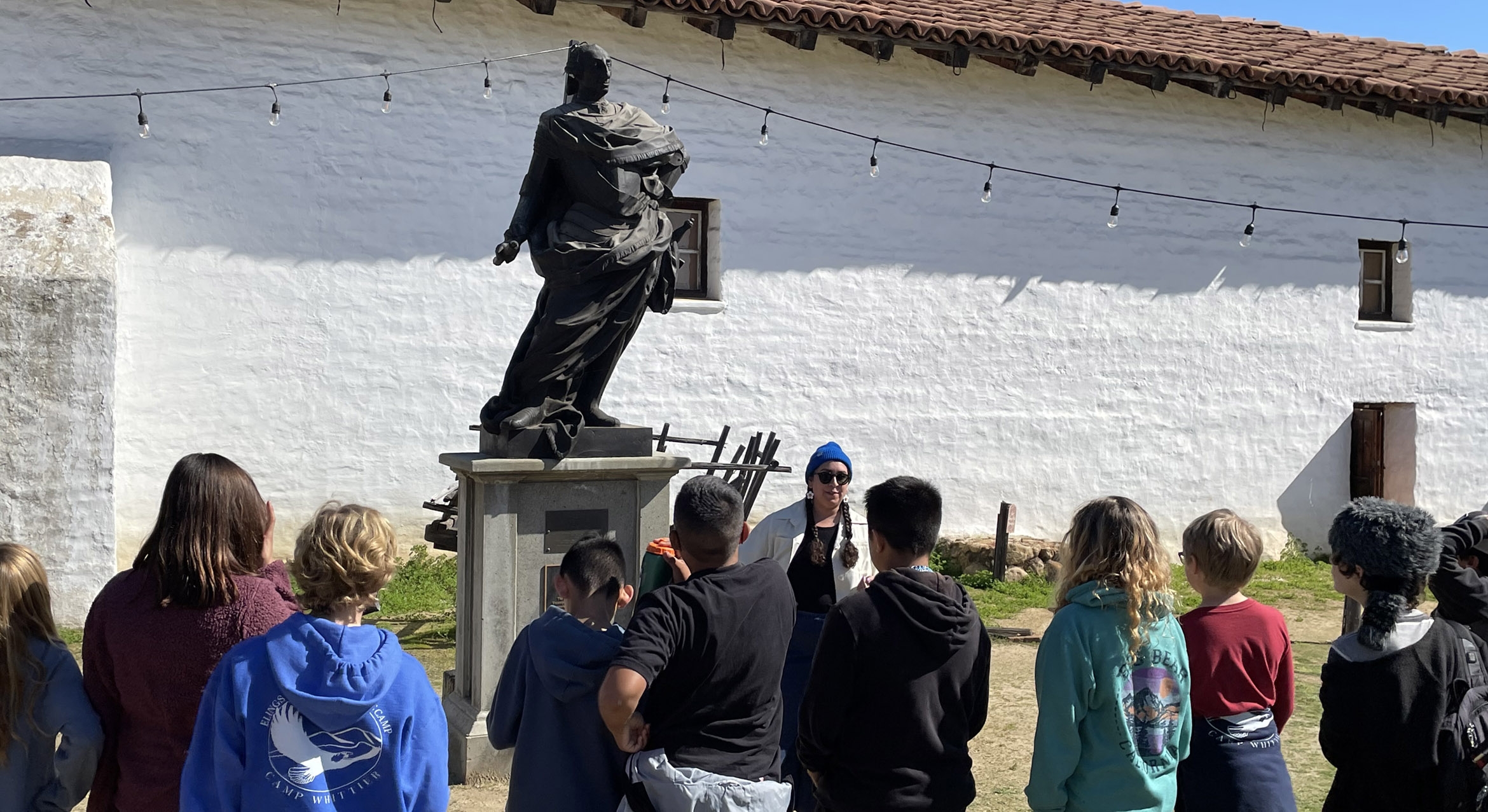 School children seen from behind observing a historical statue