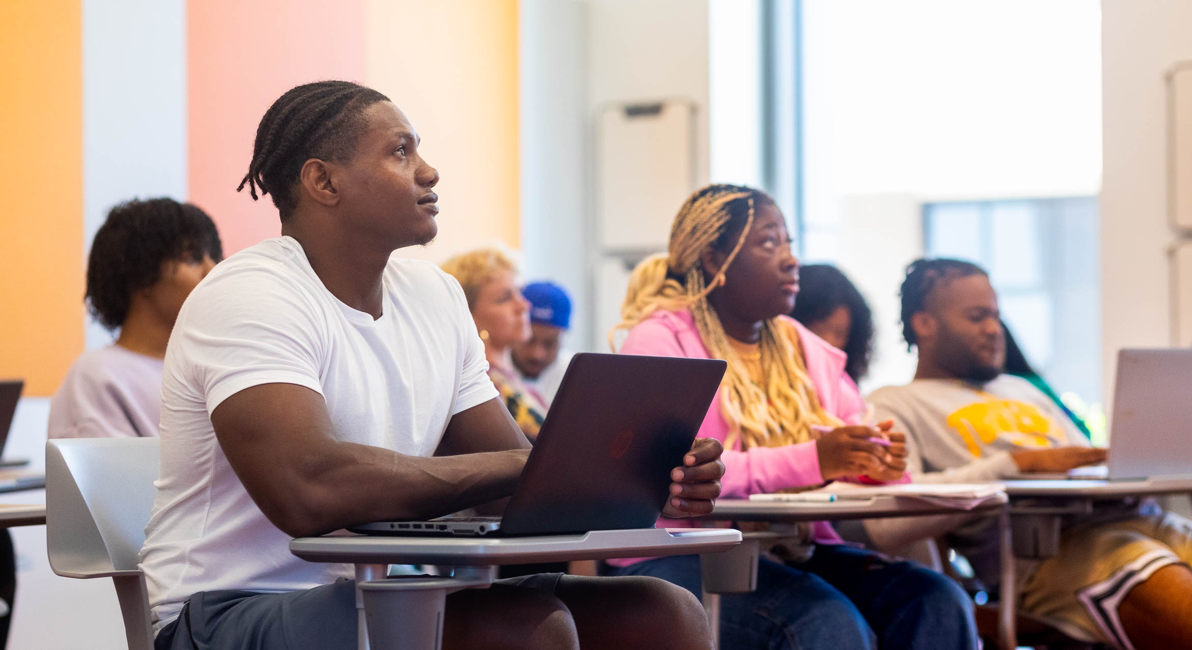 Black and African American students in a classroom with desks and laptops