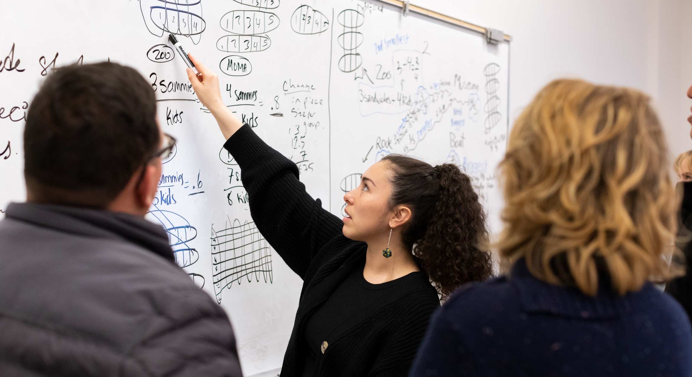 Students and professor working at a white board