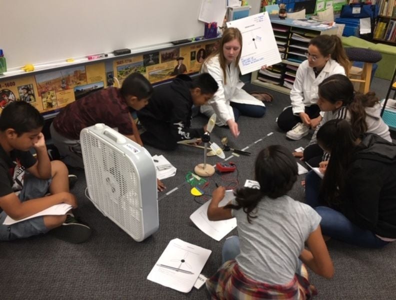 Students conduct a module on wind turbines with undergraduate volunteers.