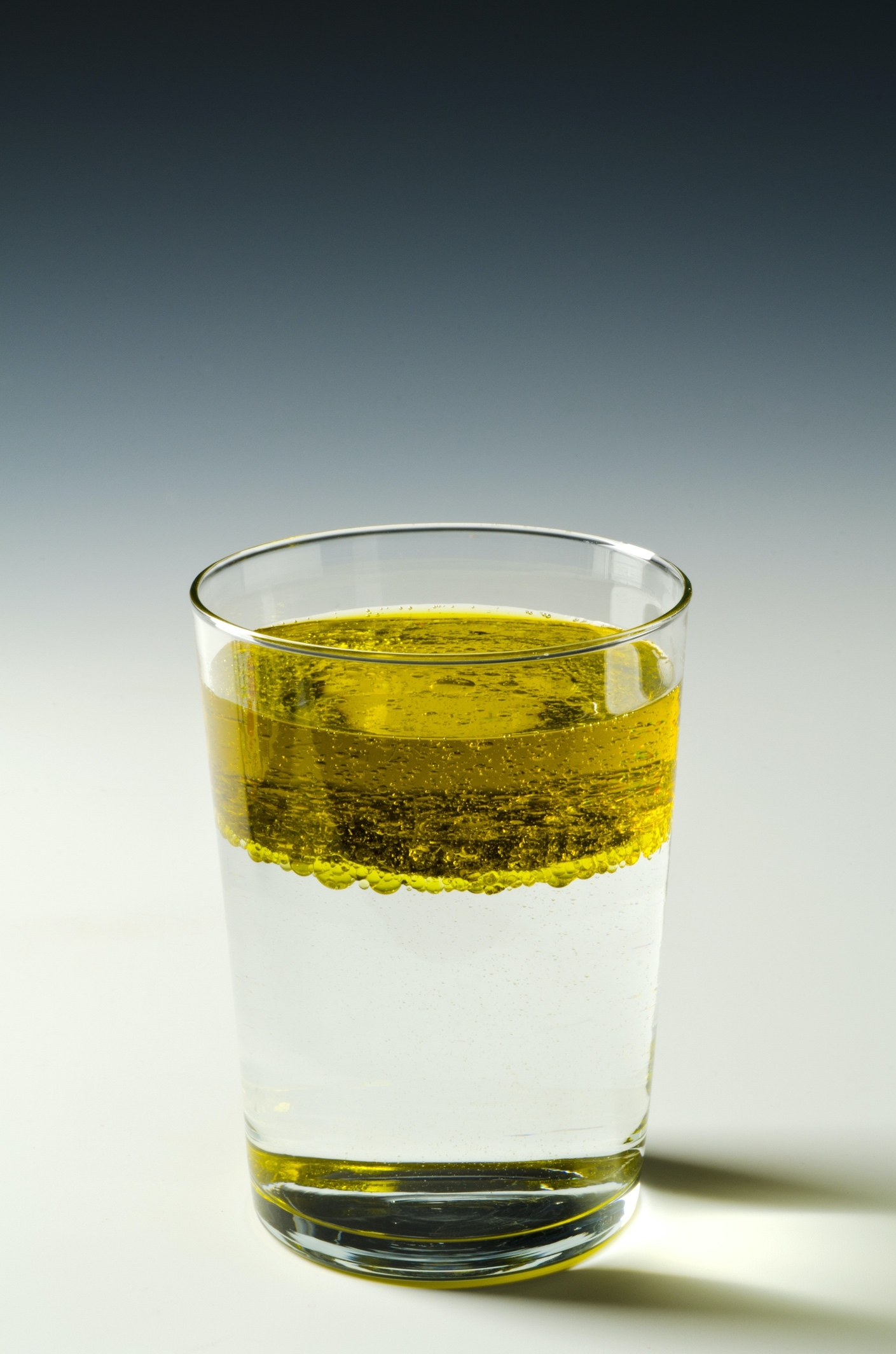 oil floating on top of water in a glass