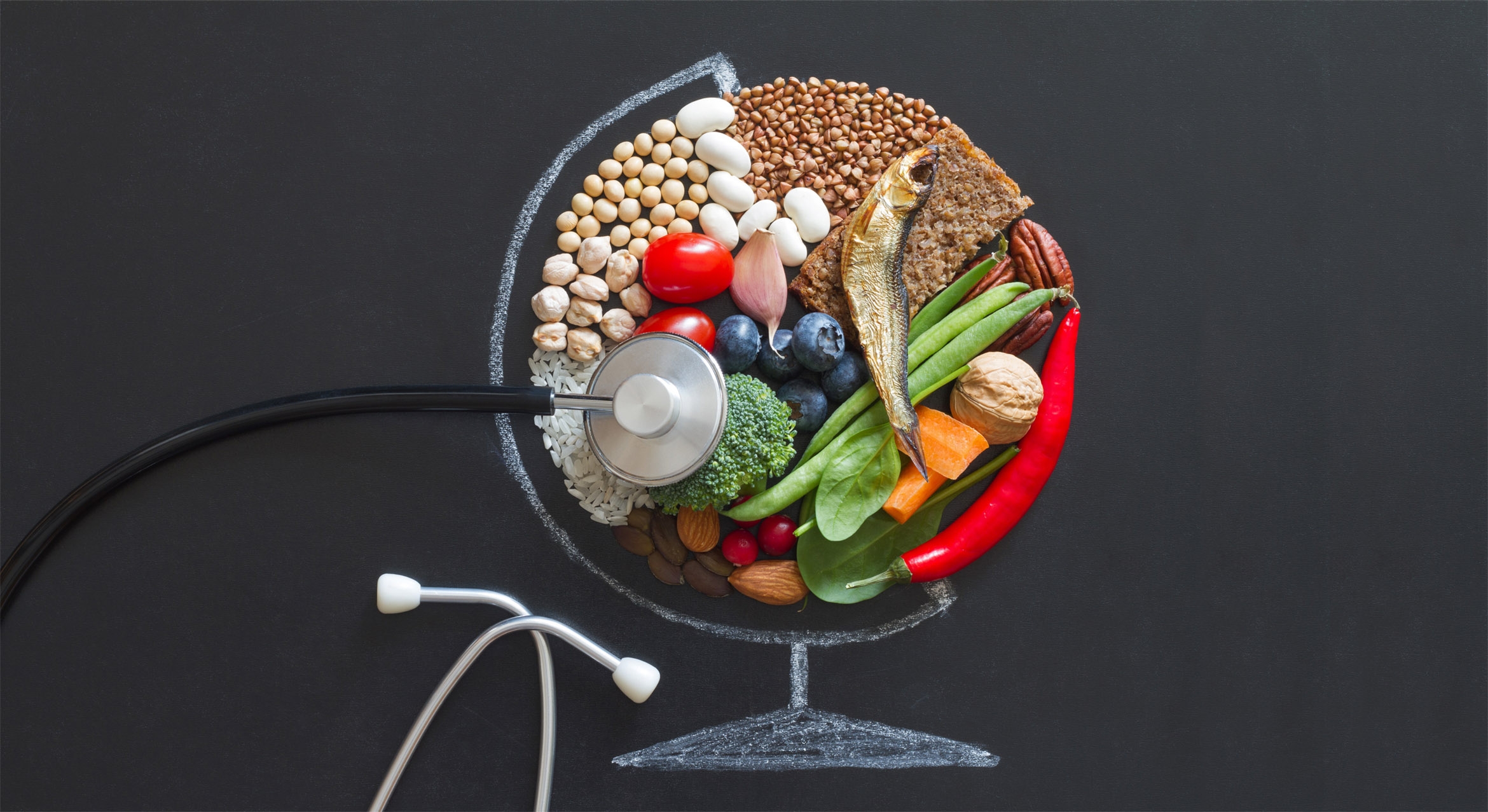 A globe made out of healthy foods with a stethoscope against a blackboard background.