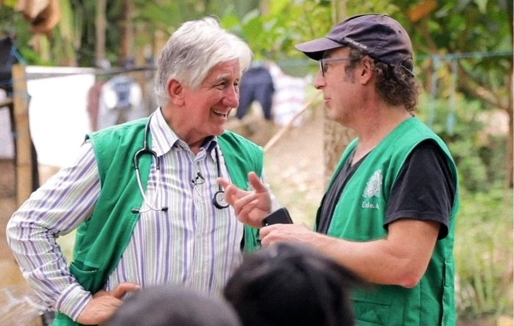 two scientists in green vests talking to each other