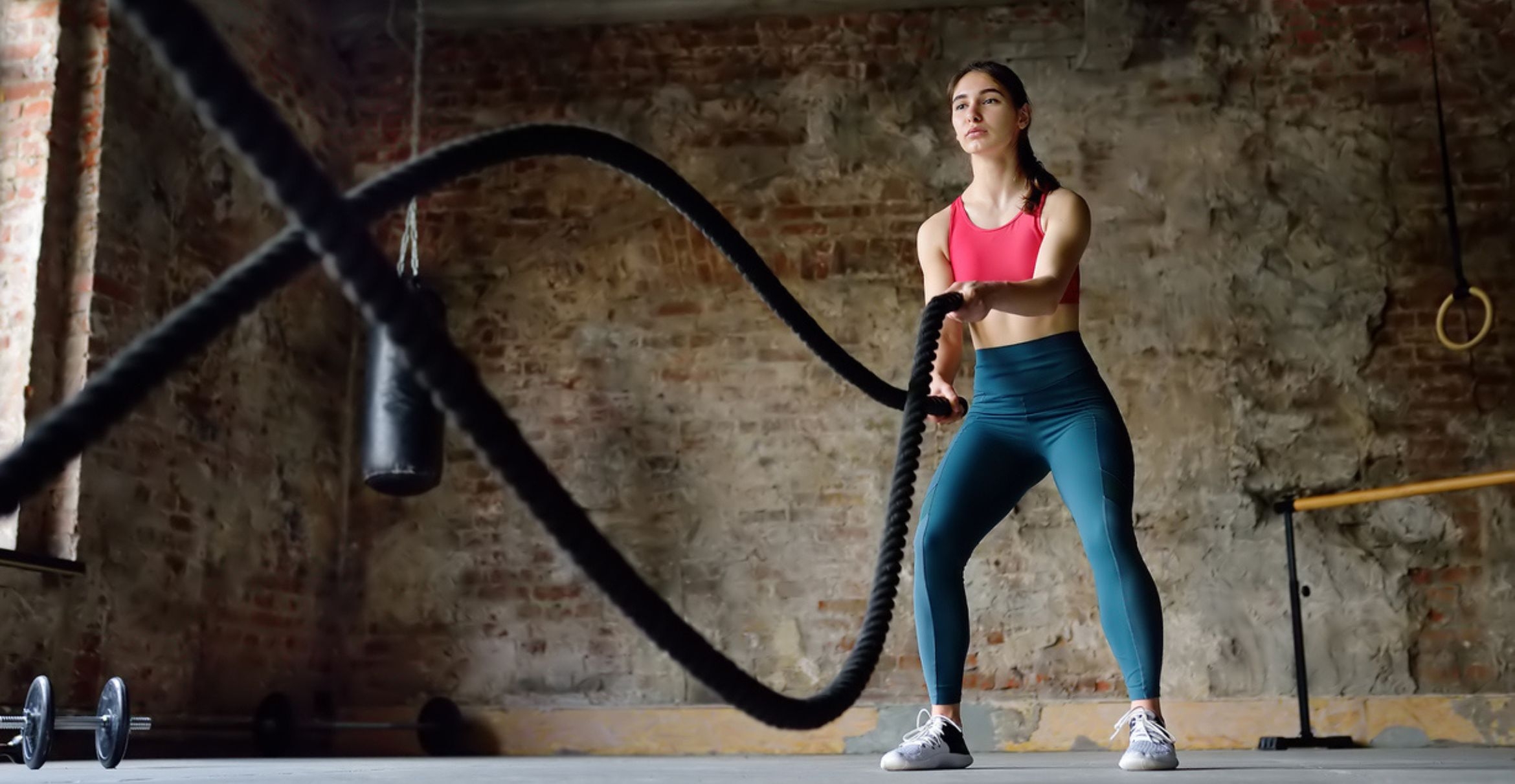 color photograph of woman exercising with battle ropes