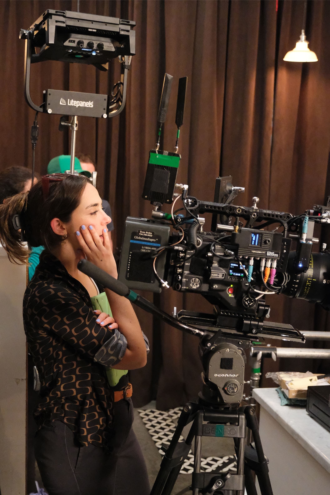 A female film director behind a movie camera with hand on her face