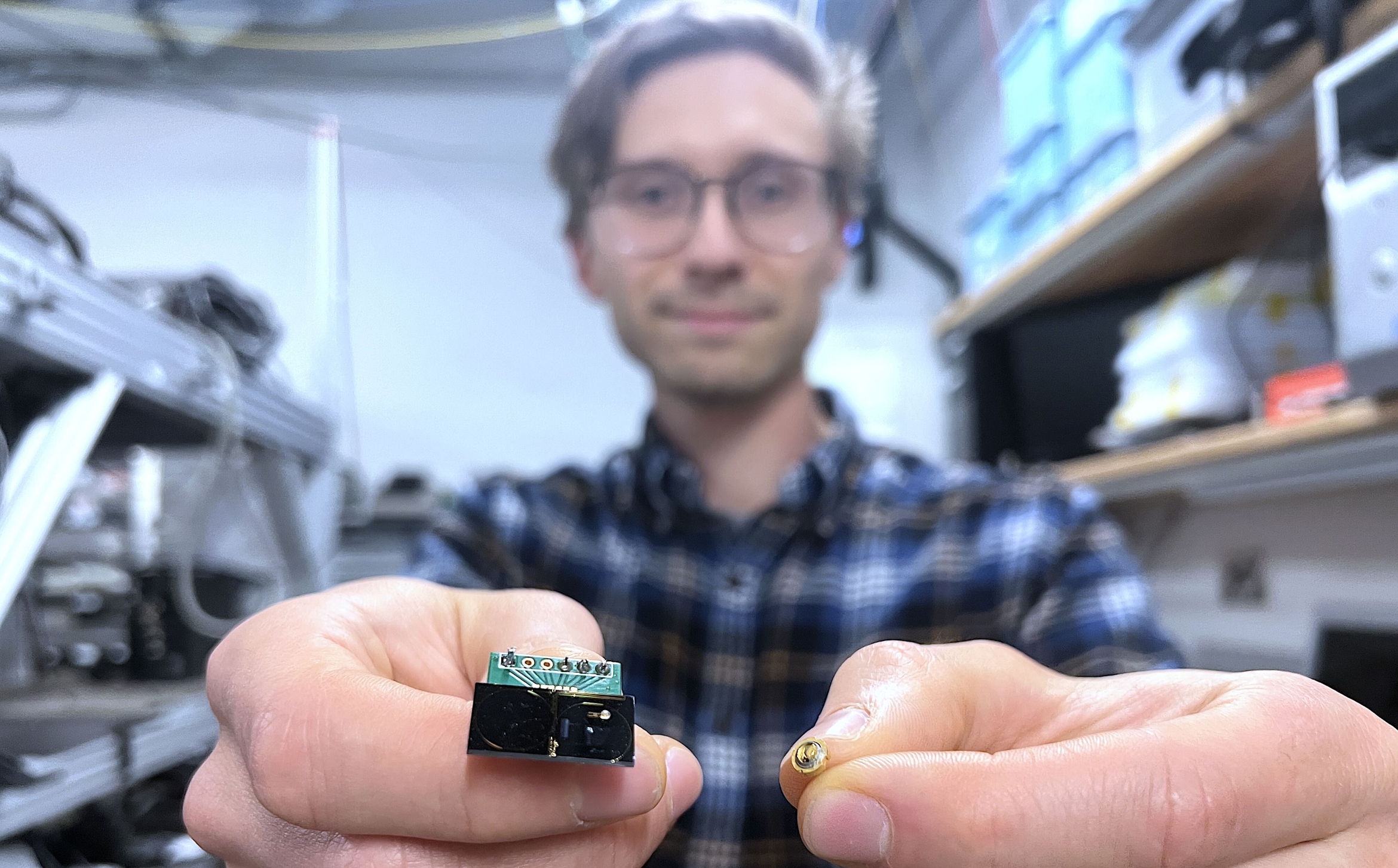 scientist holds a chip-scale ring resonator and a commercially available Fabry-Perot laser diode