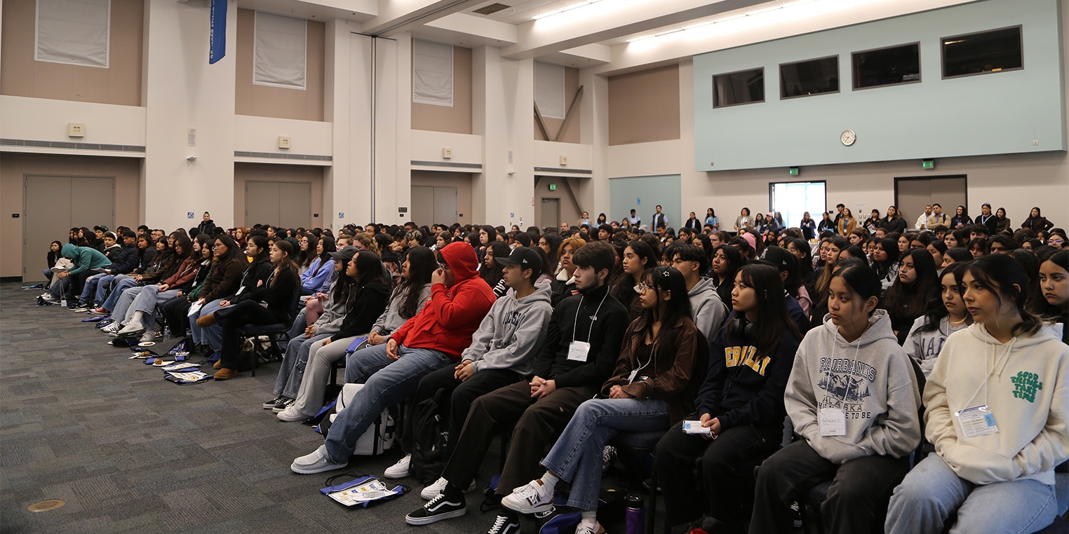 Dozens of teenage students sitting in rows in a large room