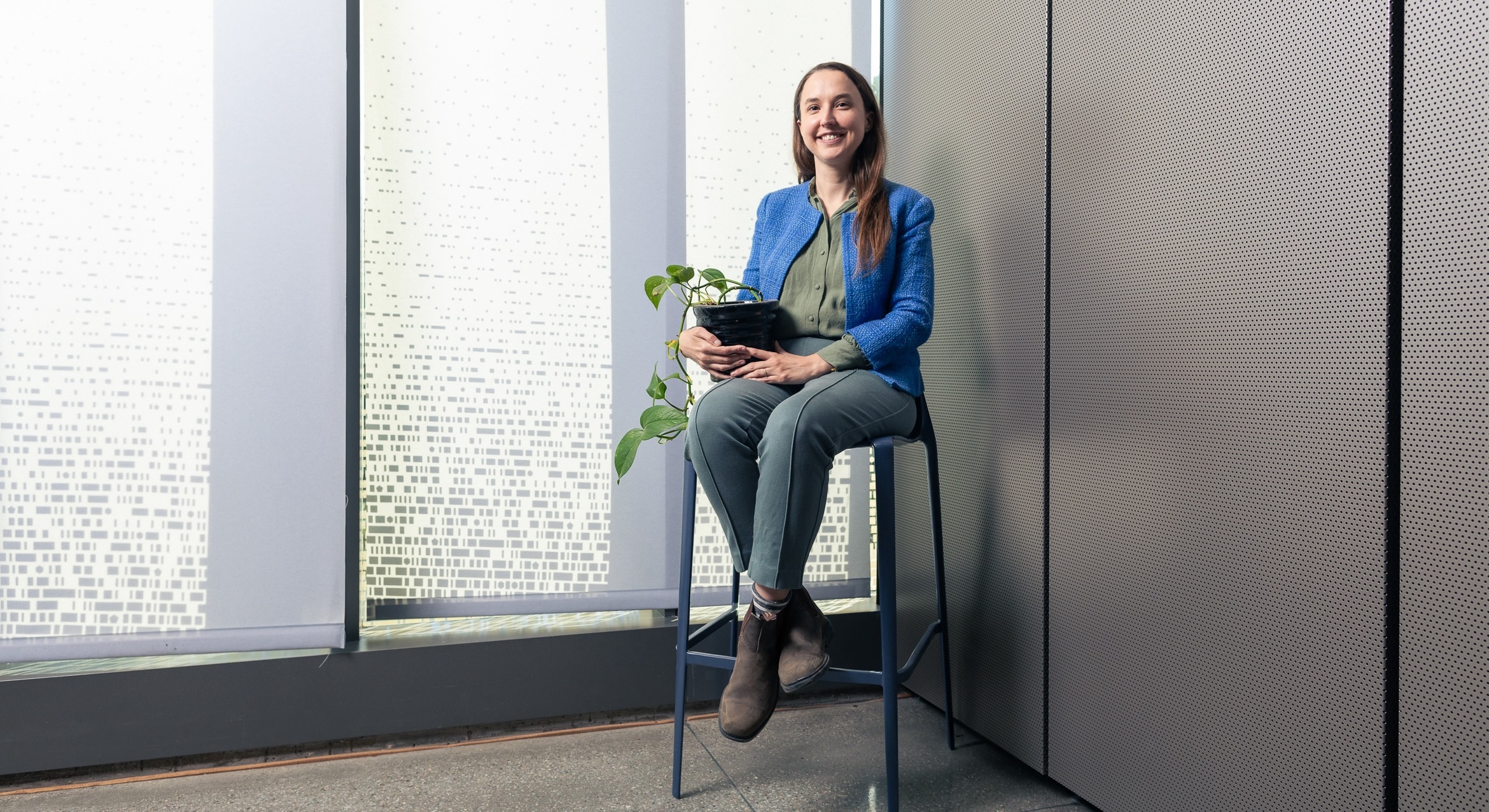 Leah Stokes on a chair holding a plant