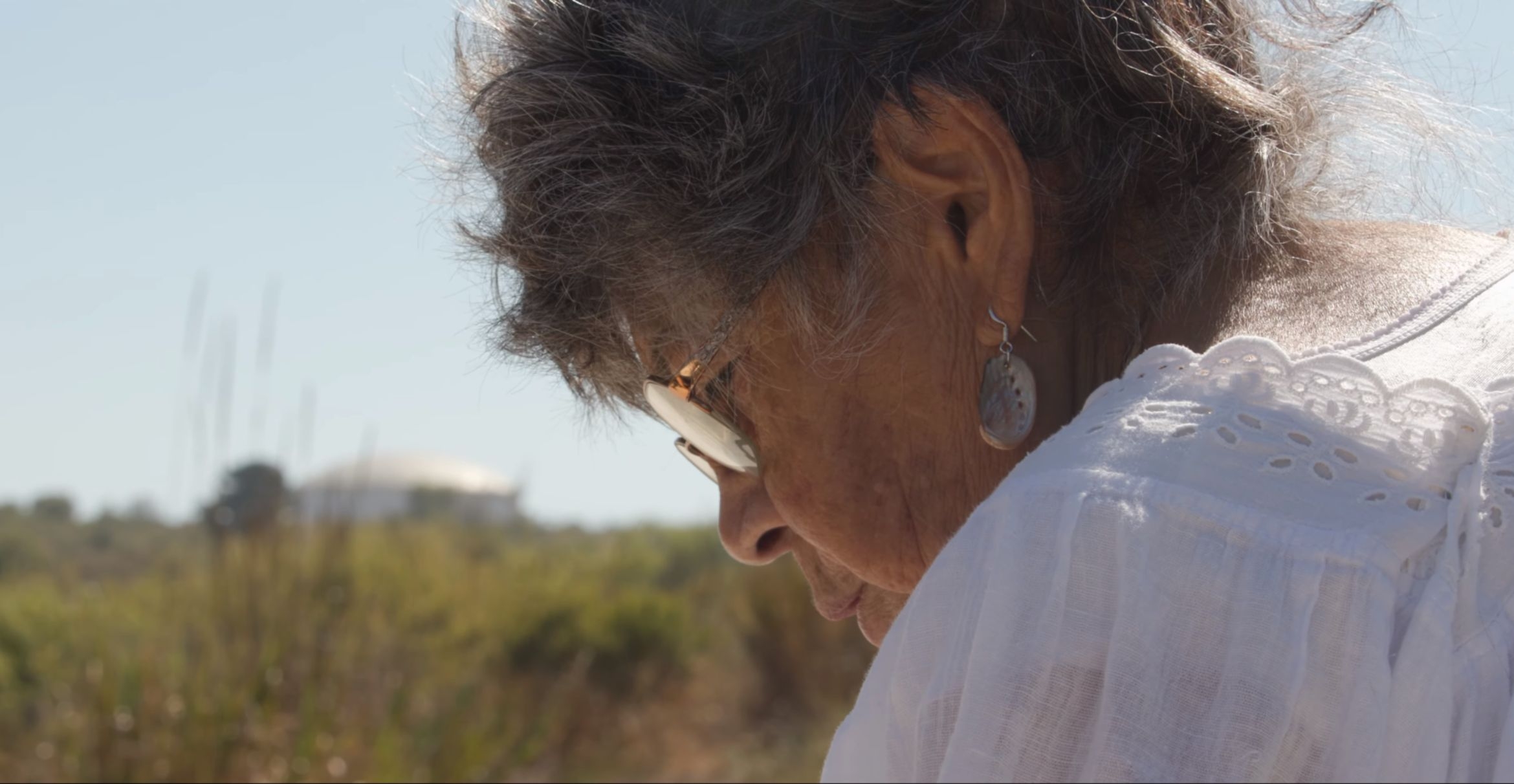 a profile photograph of an elder woman outside 