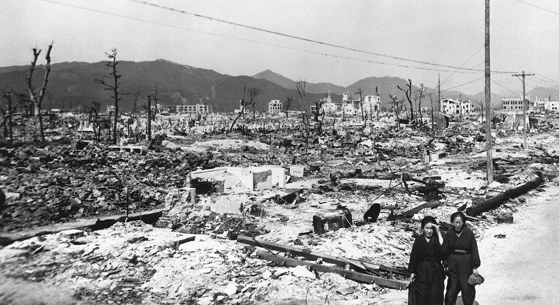 A black and white photograph of two people in the atomic devastation of World War II in Hiroshima, Japan